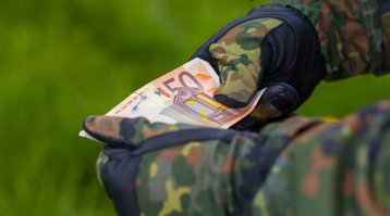 Soldat hält Geldschein mit beiden Händen